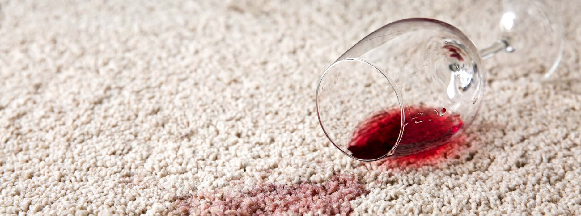 This is a photo Mile End Carpet Cleaning of red wine which has been spilt on a cream carpet. The glass is on its side.